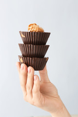 Female hand with chocolate butter cups on light background