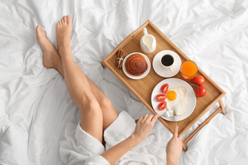 Woman having tasty breakfast in bed - obrazy, fototapety, plakaty