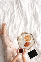 Woman having tasty breakfast in bed