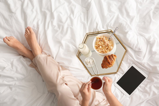 Woman having tasty breakfast in bed