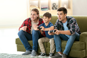 Gay couple with adopted child playing video game at home