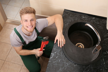 Plumber repairing sink in kitchen