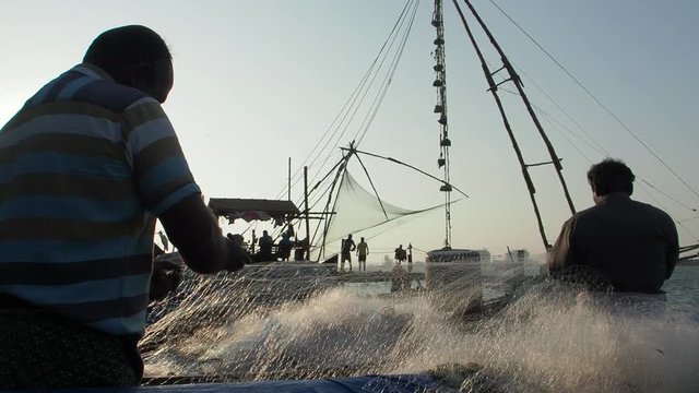 Fishermen repair their nets in front of the famed Chinese Nets in Fort Kochi, Kerala, India