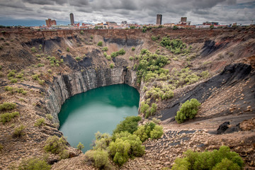 Wide view of The Big Hole in Kimberley, a result of the mining industry, with the town skyline on...