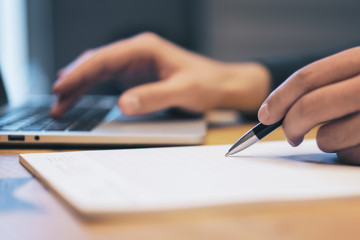 Sideview of businessman doing paperwork with laptop