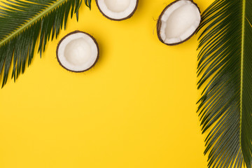 coconuts and palm leaves isolated on yellow background, top view