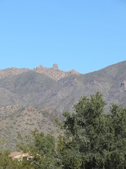 View of Tom's Thumb Trail from a distance with blue sky and trees in the foreground 