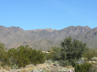 View of Tom's Thumb Trail from a distance with blue sky and trees in the foreground 
