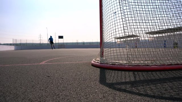  View to inline skates riding on empty playground. Outdoor inline skating on smooth concrete ground. Before the big tournament. Empty ice hockey playground - view from behind the gate. 
