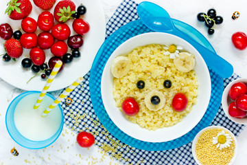 Yellow bear millet porridge with fresh berries and milk for healthy and fun kids breakfast