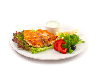 Fried sturgeon on lettuce leaves with fresh vegetables, parsley leaves, a slice of lemon and olive on a plate