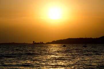 Fototapeta na wymiar beautiful sunset over beach of Toroni, Sithonia, Halkidiki, Greece, with some boats on sea and hill as silhouette
