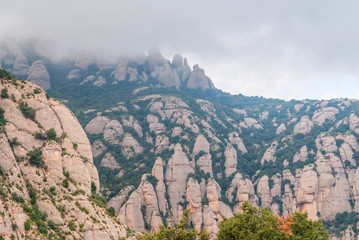 Hazy unusual mountains with green trees and cloudy sky near Montserrat Monastery,Spain