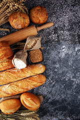 Assortment of baked bread and bread rolls on rustic grey bakery table background