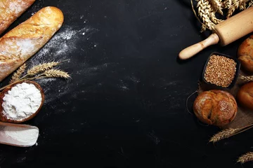 Gordijnen Assortiment van gebakken brood en broodjes op rustieke zwarte bakkerijtafelachtergrond © beats_