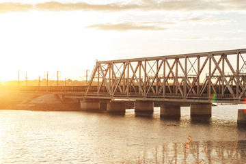 Sunset above railway bridge over water reservoir