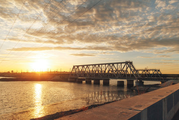 Fototapeta na wymiar Railway bridge over the river at sunset