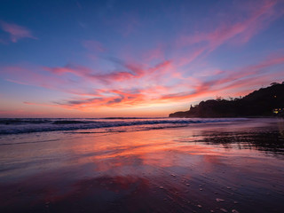 Fototapeta na wymiar Beautiful reflection of the purple sunset sky on the beach of Montanita Ecuador