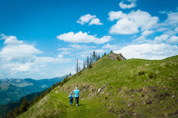 Fototapeta premium Child and parent taking a walk together on a beautiful mountain trail