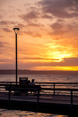 The silhouette of a couple on a bench overlooking the sunset over Puget Sound