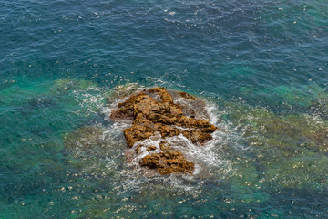Beautiful view of clear turquoise mediterranean sea waves crash on rocks at wild rocky shore....