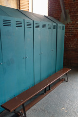 Green metal lockers with a wood bench in a sport locker room