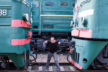 A man pushes the train. Training workout on rails. Power exercises with a locomotive on the railway. Outdoor sports.
