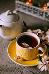 Tea served in a yellow teacup and saucer decorated with spring flowers