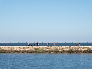 Fototapeta na wymiar People wakling on a seafront parapet and looking to a sea and water