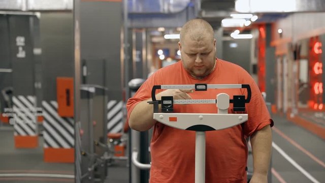Fat man is standing and using old scales for weight measurement