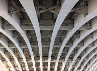 perspective view of curved arch shaped steel girders under an old road bridge with rivets and...