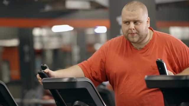 Big sweaty man is workout at fitness club in orange sportswear clothes.