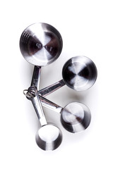 Four stainless steel measuring cups clipped together over white