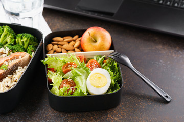 Takeaway lunch boxes with food at working desk with laptop.