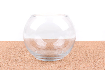 Clear glass bowl on a plain cork board background