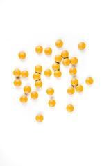 Scattered orange yellow pills over a white background