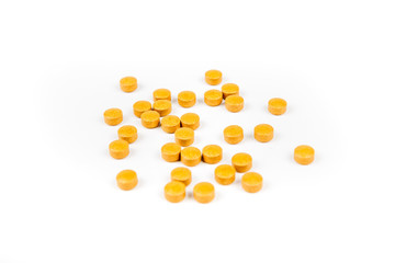 Scattered orange yellow pills over a white background