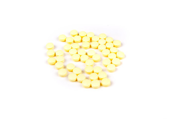 Scattered yellow pills over a white background