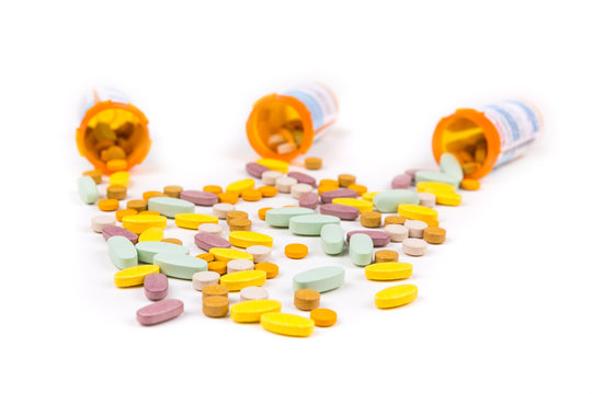 Pile of multicolored pills in front of prescription bottles