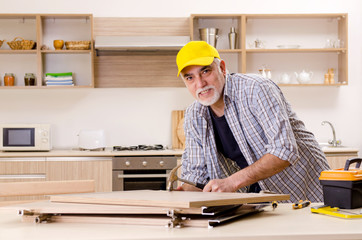 Aged contractor repairman working in the kitchen 