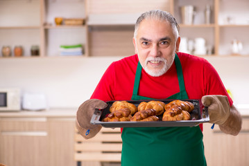 Old male baker working in the kitchen 