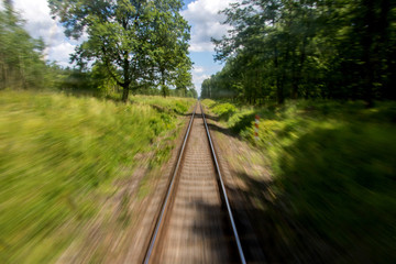 Fototapeta premium Defocused railroad tracks in summer nature behind a passing train