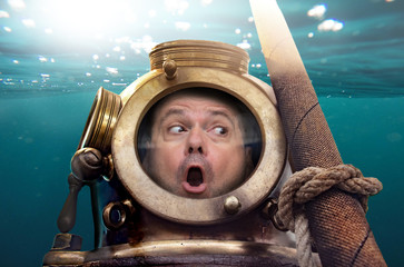 Portrait of man in old diving suit and helmet under water. Funny diver in retro equipment in...