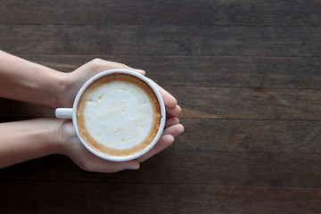 Top view female hands holding cups of coffee table background
