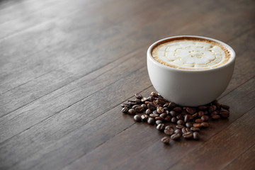 Coffee cup on table has a coffee bean around
