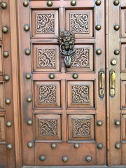 Puerta de madera en cedro, con adornos de bronce y picaporte con figura de  León.
