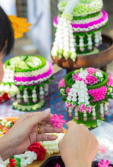 Thai woman making a tradition Thai flowers garland activities in Songkran festival, Bangkok Thailand.