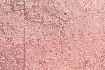 Blurred abstract background. The texture of the painted concrete rough surface with cracks and holes of a delicate pink color. Cropped shot, horizontal, place for text, nobody. The concept of repair 