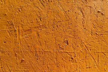 Blurred abstract background. The texture of a painted concrete rough surface with cracks and holes orange color. Cropped shot, horizontal, place for text, nobody. The concept of repair and design.