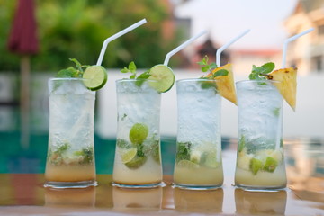 pineapple mojito cocktail and lime mojito cocktail at swim pool background